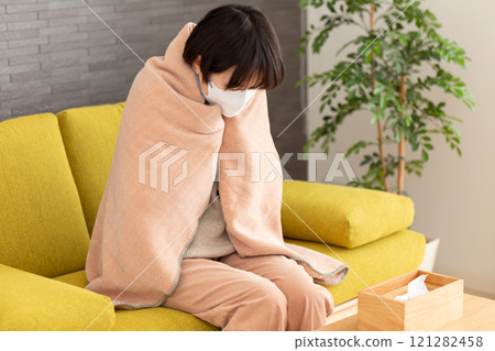 一位中年婦女在冬天的房間裡蓋著毯子感到寒冷。 一位中年婦女在冬天的房間裡蓋著毯子感到寒冷。 121282458