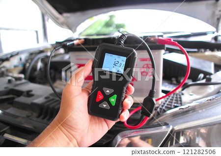 Car battery voltage tester in use under the hood of car by auto technician , Car repair concept Car battery voltage tester in use under the hood of car by auto technician , Car repair concept 121282506