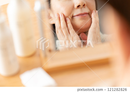 Middle-aged to senior women doing skin care while looking in the mirror 121282826