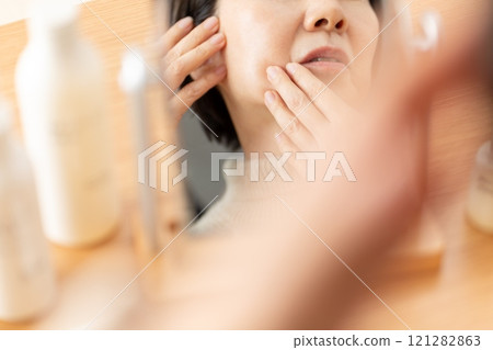 Middle-aged to senior women doing skin care while looking in the mirror 121282863