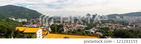 Panoramic view of George Town in Penang, Malaysia showcasing skyline, residential areas, green hills, and traditional buildings under partly cloudy sky, highlighting cityscape diversity 121283155