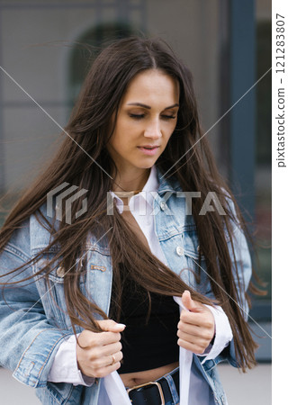 Caucasian woman with long brown hair is wearing a blue jeans jacket and a white shirt Caucasian woman with long brown hair is wearing a blue jeans jacket and a white shirt 121283807