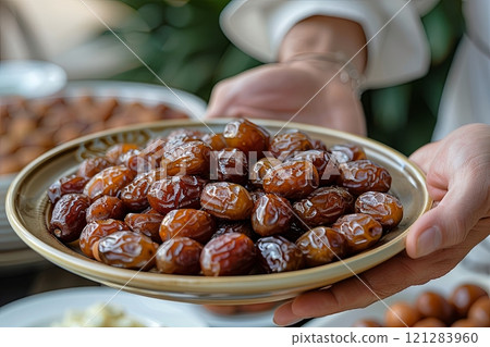 Person is holding a plate of dates 121283960