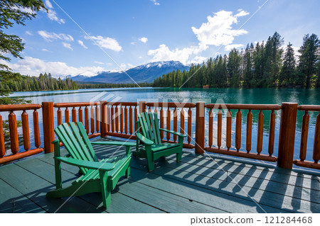 Jasper National Park summer landscape, Alberta, Canada. Adirondack chairs on lakeside of the Beauvert Lake (Lac Beauvert). Snowcapped Whistlers Peak mountain in the background. Jasper National Park summer landscape, Alberta, Canada. Adirondack chairs on lakeside of the Beauvert Lake (Lac Beauvert). Snowcapped Whistlers Peak mountain in the background. 121284468