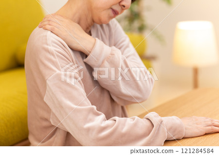 Middle-aged to senior women suffering from stiff shoulders in the living room on a winter night 121284584