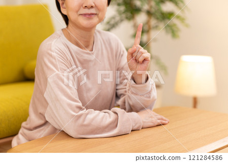 冬夜,中高級女性在客廳舉起食指 冬夜,中高級女性在客廳舉起食指 121284586