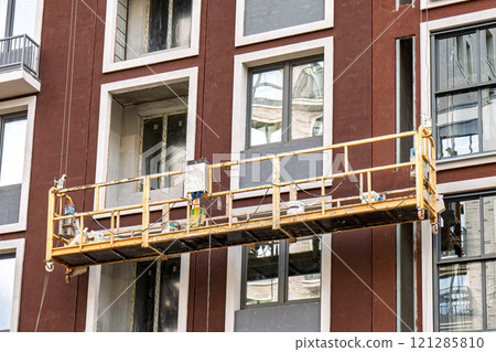 Construction suspended scaffold in front of modern building facade Construction suspended scaffold in front of modern building facade 121285810