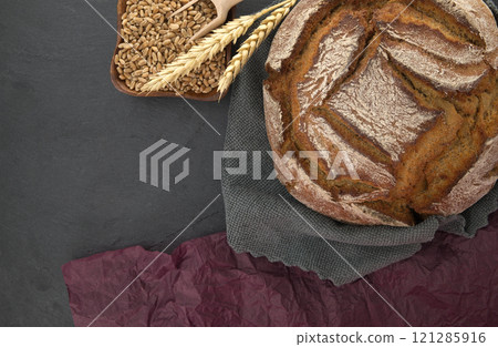 Bread loaf and wheat grain on a gray kitchen towel Bread loaf and wheat grain on a gray kitchen towel 121285916