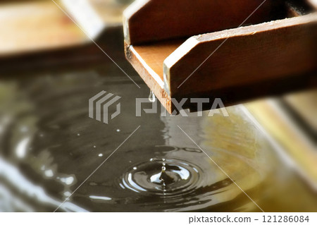 從露天檜木浴池的出水口落下的一滴水和漣漪 從露天檜木浴池的出水口落下的一滴水和漣漪 121286084