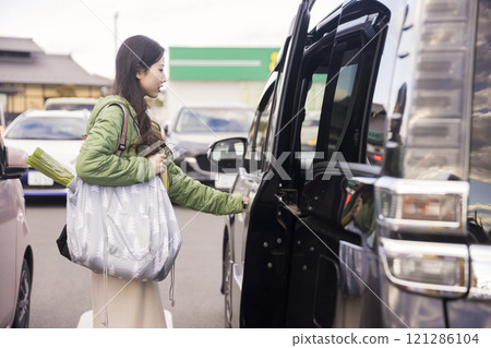 A woman putting groceries into her car in a supermarket parking lot A woman putting groceries into her car in a supermarket parking lot 121286104