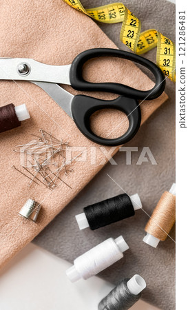 Sewing essentials. Scissors, tape measure, pins, and various thread colors for crafts 121286481