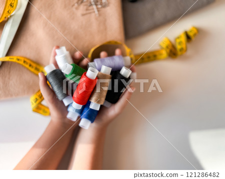 Colorful threads and measuring tape in crafting hands 121286482