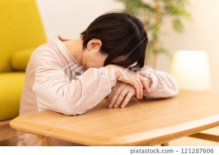 冬夜,穿著睡衣的中高級女性在客廳顯得沮喪 冬夜,穿著睡衣的中高級女性在客廳顯得沮喪 121287606