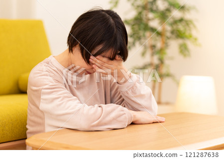 A middle-aged to senior woman in pajamas feeling depressed in the living room on a winter night 121287638