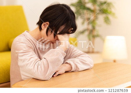 A middle-aged to senior woman in pajamas feeling depressed in the living room on a winter night 121287639