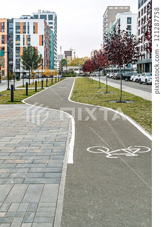 Modern urban bike path with trees and buildings in background Modern urban bike path with trees and buildings in background 121287758