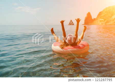 Summer vacation woman in hat floats on an inflatable donut mattress. Happy woman relaxing and enjoying family summer travel holidays travel on the sea. Summer vacation woman in hat floats on an inflatable donut mattress. Happy woman relaxing and enjoying family summer travel holidays travel on the sea. 121287795