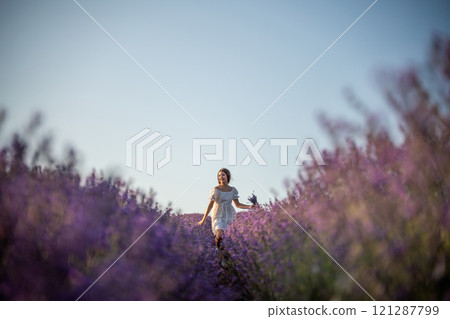 Lavender field happy girl in white dress with a scythe runs through a lilac field of lavender. Aromatherapy travel Lavender field happy girl in white dress with a scythe runs through a lilac field of lavender. Aromatherapy travel 121287799