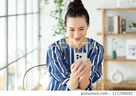 A young woman looking at a smartphone at home 121290092