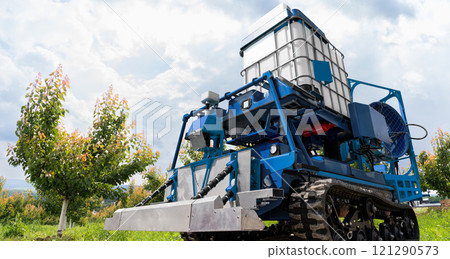 Autonomous robot sprayer works in a fruit garden. Smart farming concept. Autonomous robot sprayer works in a fruit garden. Smart farming concept. 121290573