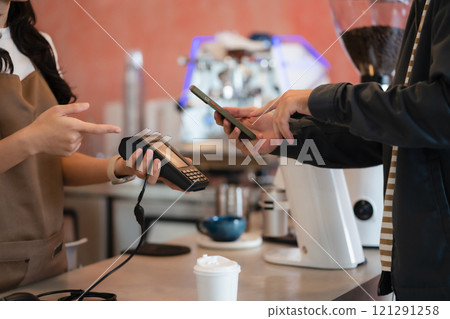Closeup shot of cashier hands. Seller using touch smartphone for accepting client customer payment. Small business of coffee shop. 121291258