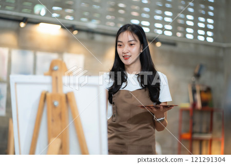 Young female artist painting on canvas in the home studio, fine arts and creativity concept. 121291304