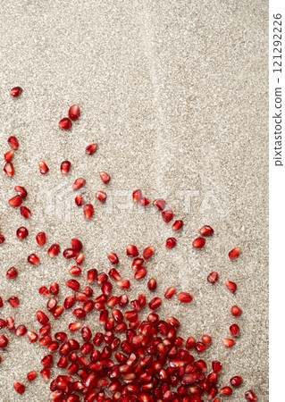 Scattered pomegranate seeds on a gray stone background, place for text 121292226