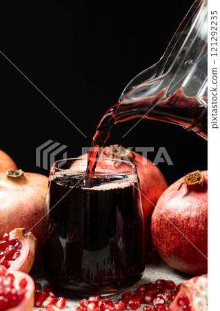 Pomegranate juice pouring from jug into glass 121292235