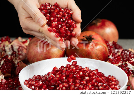A handful of pomegranate seeds, seeds pouring out of hands 121292237