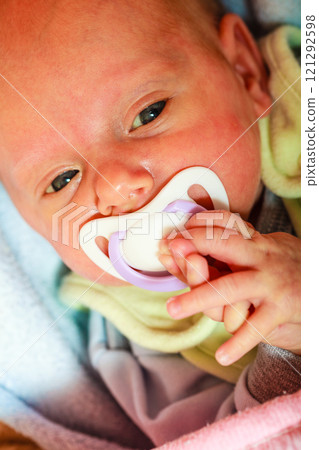 Closeup of little newborn lying with teat in mouth Closeup of little newborn lying with teat in mouth 121292598