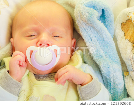 Closeup of little newborn sleeping with teat in mouth 121292608