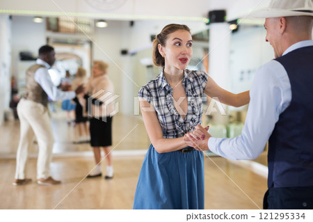 Cheerful female practicing lindy hop in pair with man Cheerful female practicing lindy hop in pair with man 121295334