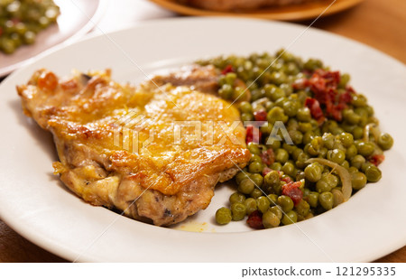 Fried boneless skinless chicken leg with green peas for garnish on plate Fried boneless skinless chicken leg with green peas for garnish on plate 121295335