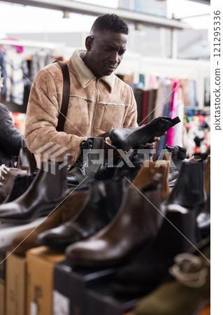 Man examines new shoes at a flea market Man examines new shoes at a flea market 121295336