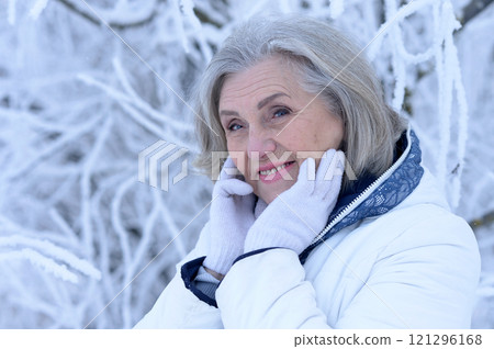 Beautiful elderly woman posing in a snowy winter park Beautiful elderly woman posing in a snowy winter park 121296168