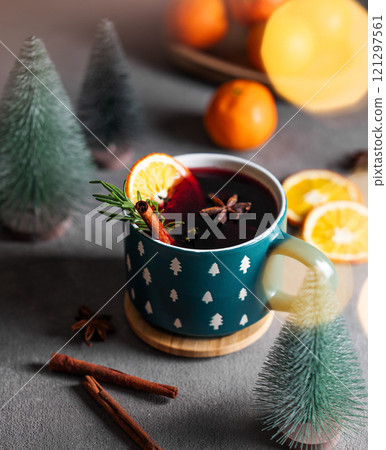Mulled wine with orange, cinnamon and rosemary in a cup on a dark background with tangerines 121297561