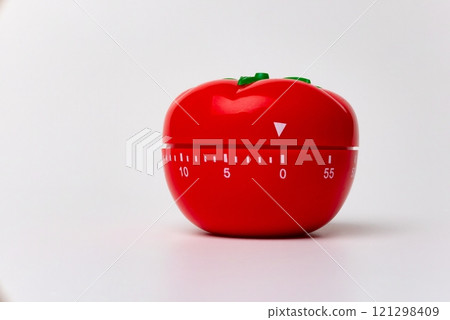 Close up view of mechanical tomato shaped kitchen clock timer for cooking and studying. Used for pomodoro technique for time & productivity management. Isolated on white background, set at 5 minutes. Close up view of mechanical tomato shaped kitchen clock timer for cooking and studying. Used for pomodoro technique for time & productivity management. Isolated on white background, set at 5 minutes. 121298409