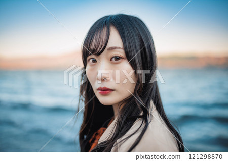 藍天、湖泊和穿著風衣的年輕女子 藍天、湖泊和穿著風衣的年輕女子 121298870