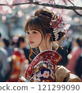 A young woman in a kimono standing in front of a cherry blossom 121299090