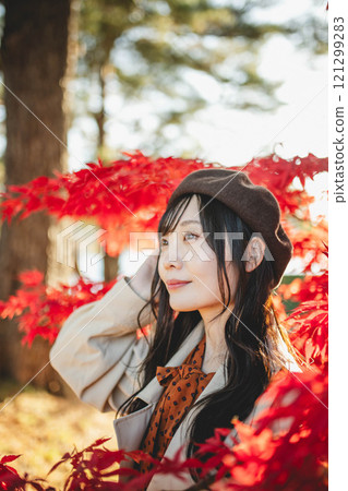 A young woman wearing a beret looking at autumn leaves A young woman wearing a beret looking at autumn leaves 121299283