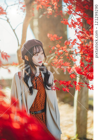 A young woman wearing a beret looking at autumn leaves A young woman wearing a beret looking at autumn leaves 121299290