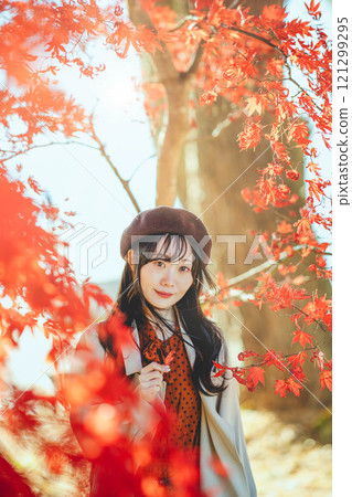 A young woman wearing a beret looking at autumn leaves A young woman wearing a beret looking at autumn leaves 121299295