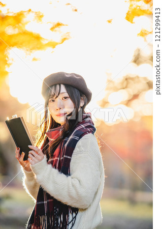 秋季閱讀:一位年輕女子在秋葉公園讀書 秋季閱讀:一位年輕女子在秋葉公園讀書 121299413