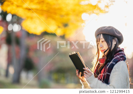 秋季閱讀：一位年輕女子在秋葉公園讀書 121299415