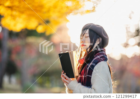 Autumn reading: A young woman reading in a park with autumn leaves 121299417