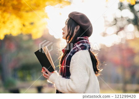 Autumn reading: A young woman reading in a park with autumn leaves Autumn reading: A young woman reading in a park with autumn leaves 121299420