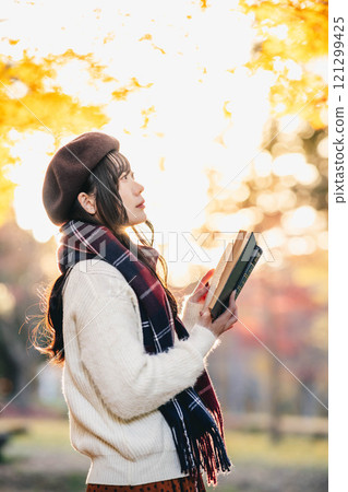 Autumn reading: A young woman reading in a park with autumn leaves 121299425