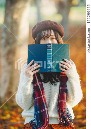 Autumn reading: A young woman reading in a park with autumn leaves Autumn reading: A young woman reading in a park with autumn leaves 121299433