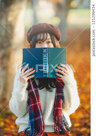 Autumn reading: A young woman reading in a park with autumn leaves 121299434