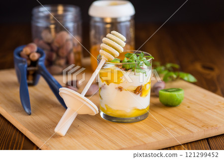 homemade yogurt with kiwi, honey and nuts in a glass on a wooden table 121299452